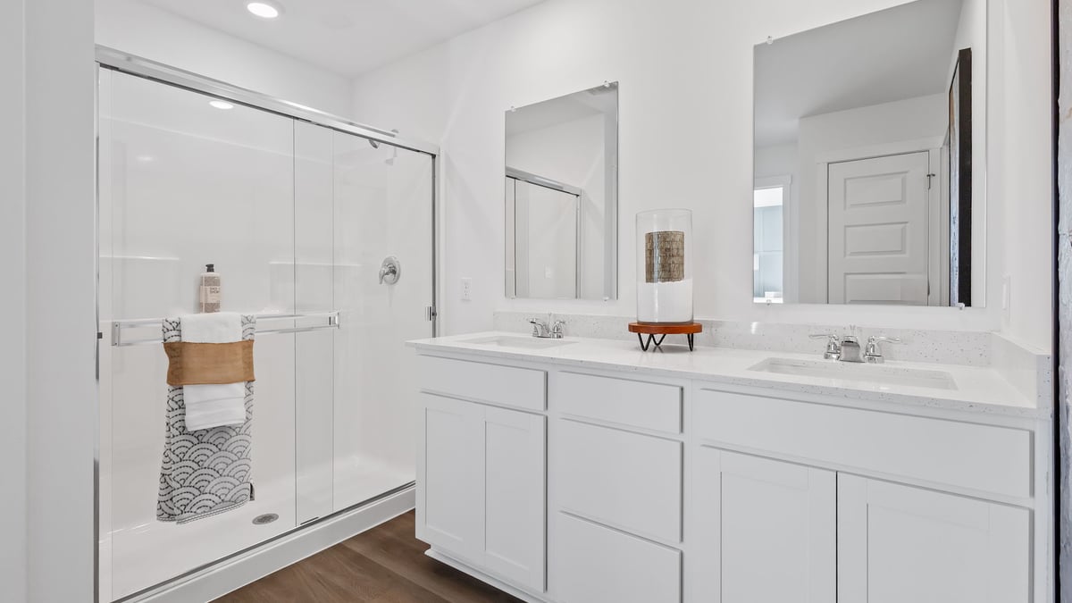 Primary bathroom with dual vanity sinks and a walk-in shower.