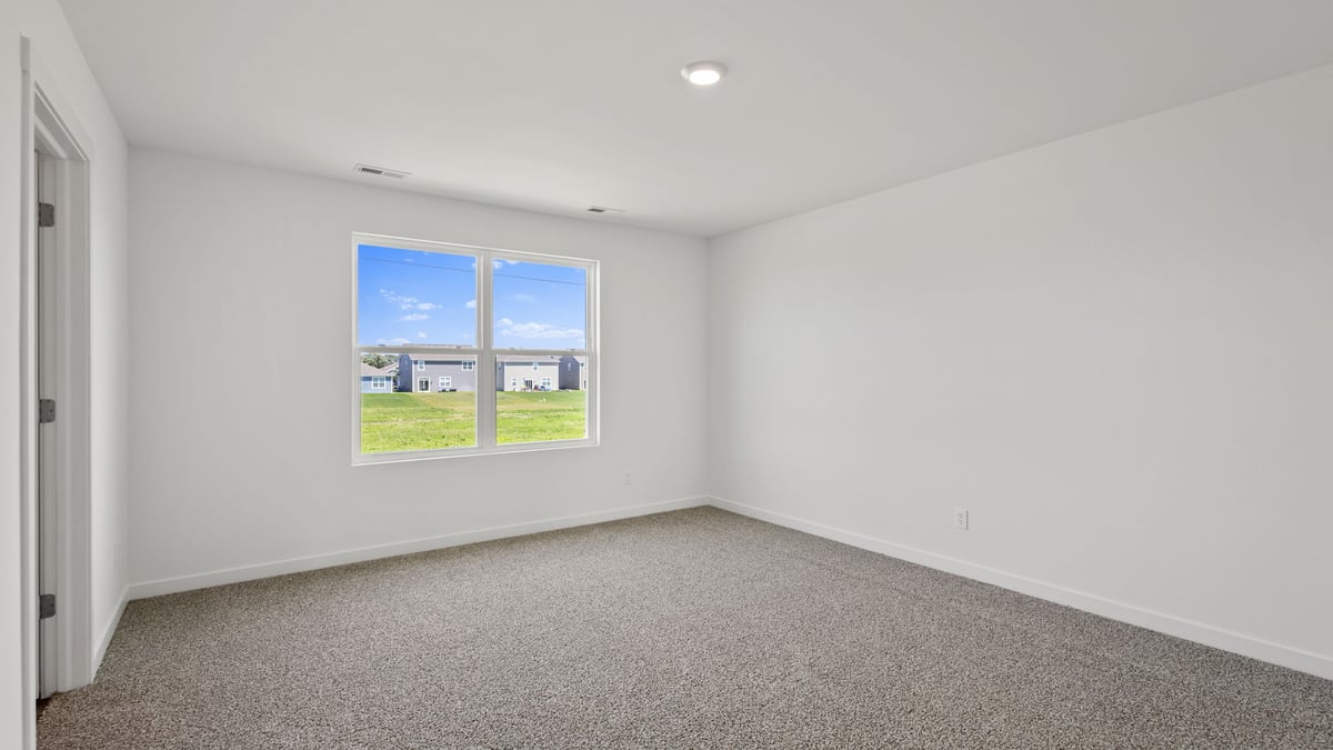 Primary bedroom with carpeted floors and a big window.