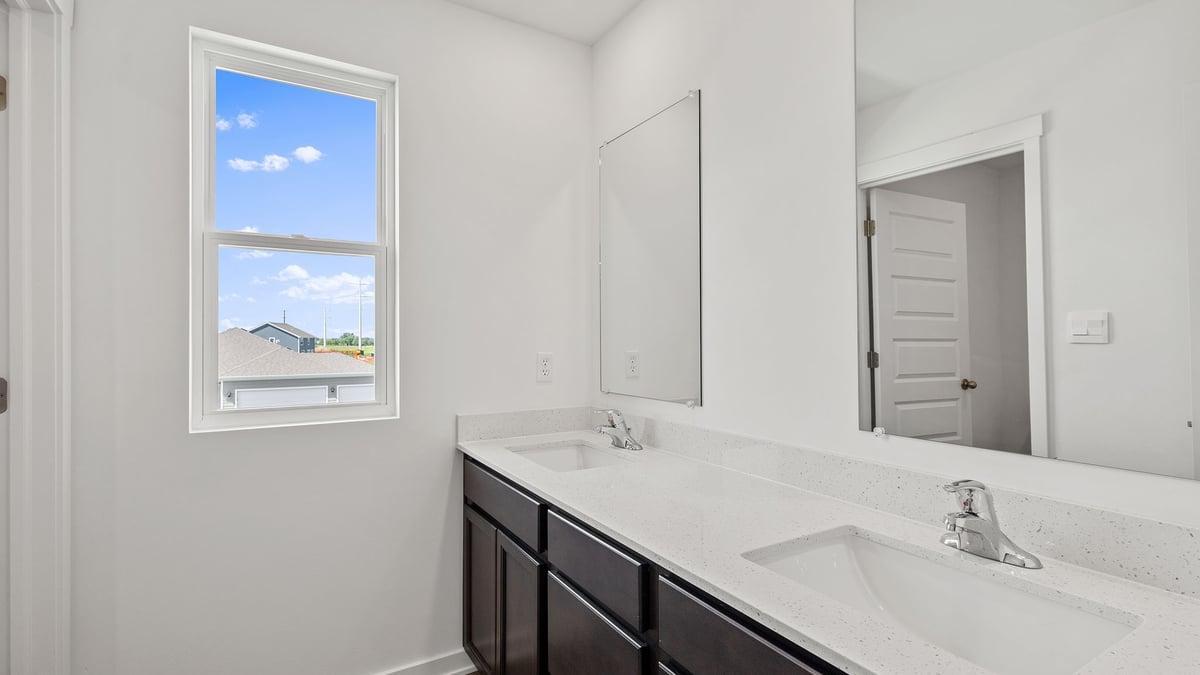 Bathroom with dual vanity sinks and a side window.