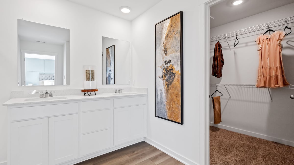 Primary bathroom with dual vanity sinks and a walk-in closet.