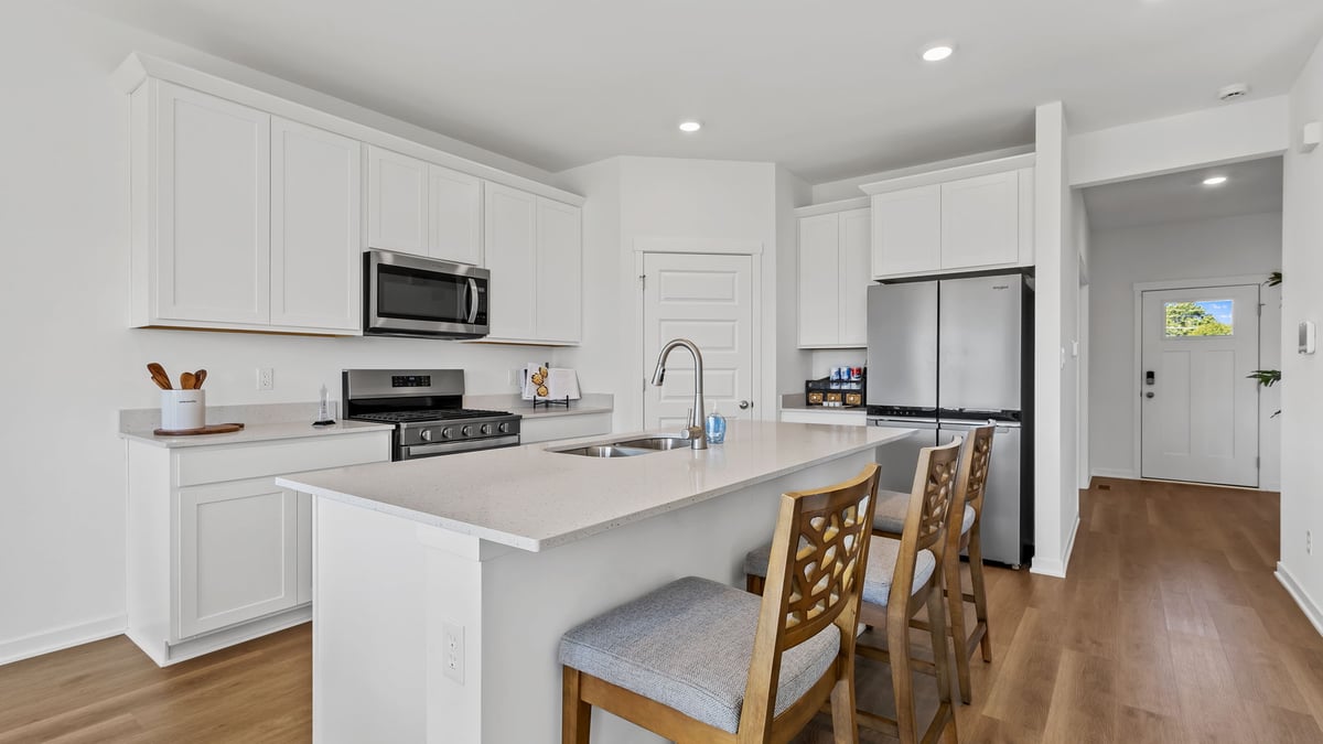 Kitchen with white cabinets and hard wood flooring.