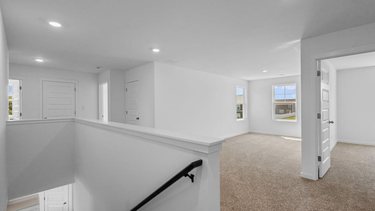 Top of stair on second floor with view of loft room.