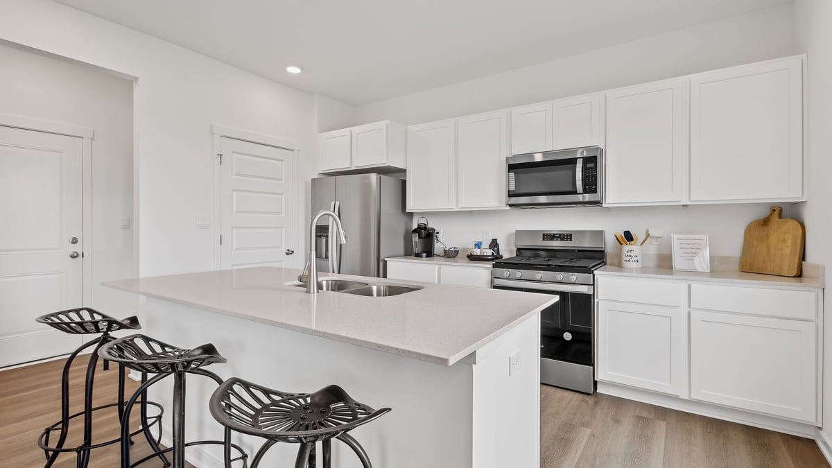 Kitchen with white cabinets with hard wood flooring.