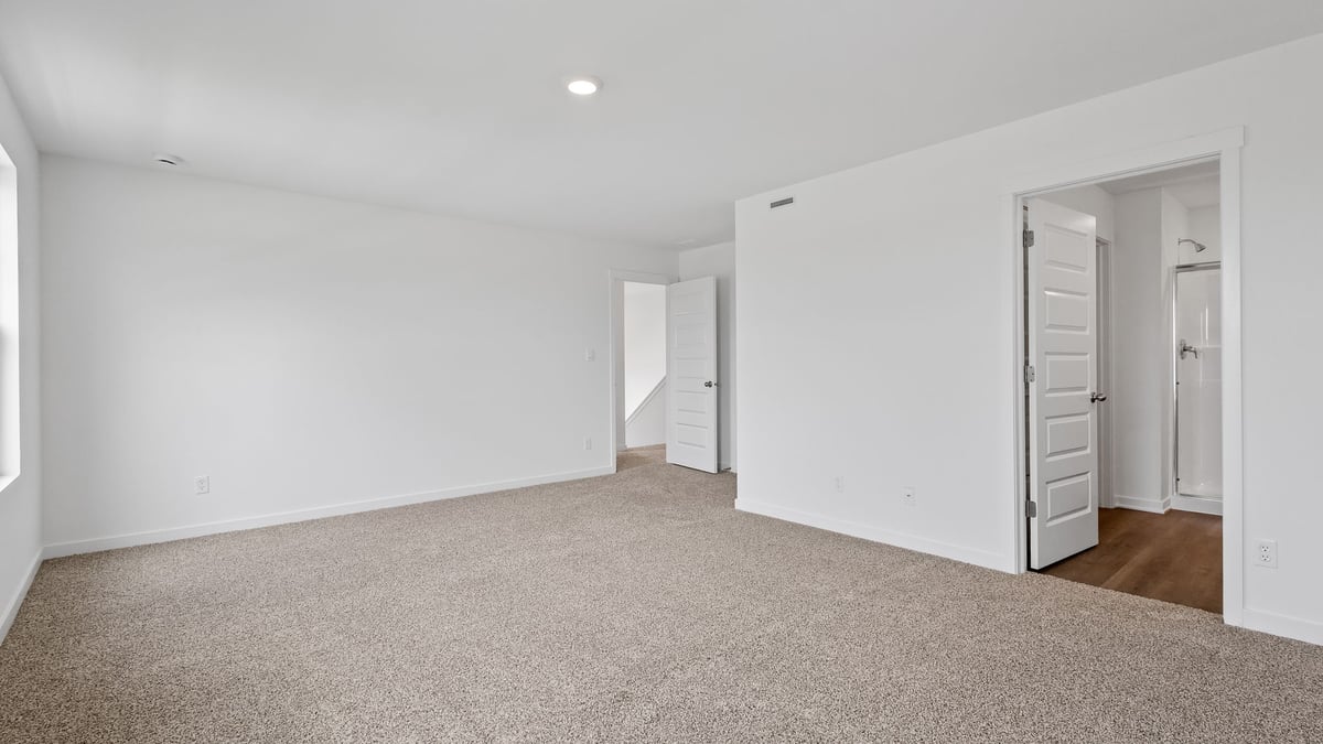 Primary bedroom with carpeted floors and own bathroom.