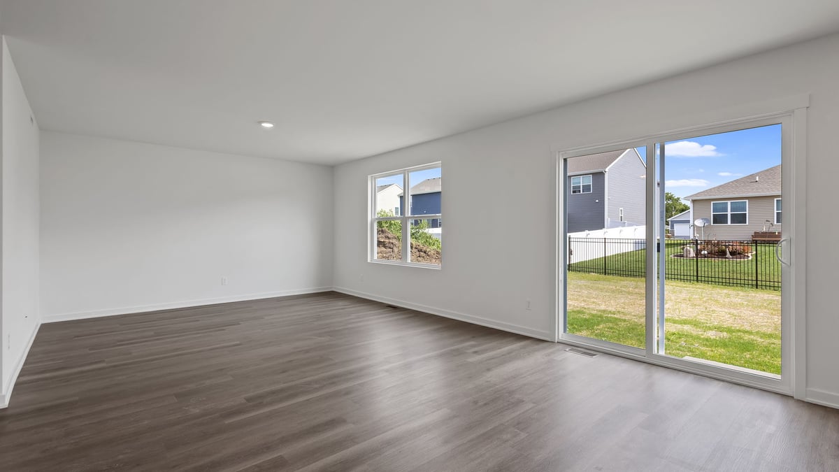 Living room area with hard wood floors and windows with a glass sliding doors.
