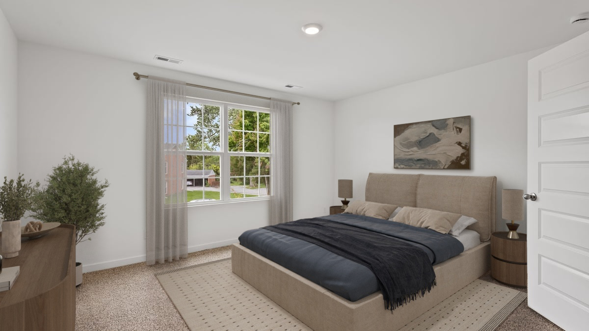 Primary bedroom with a big window and carpeted floors.