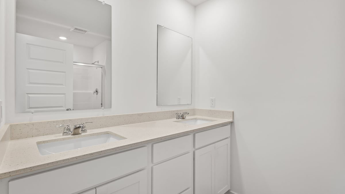 Bathroom with dual vanity sinks and white cabinets.