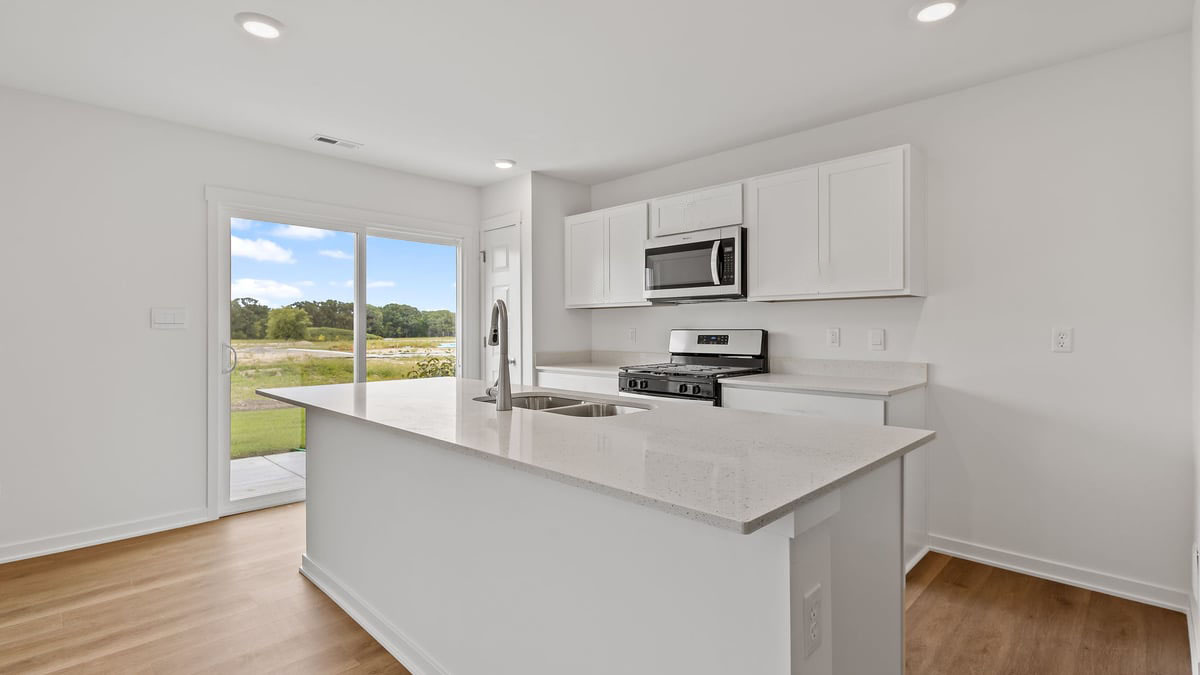 Kitchen with white cabinets and a glass sliding door with hard wood floors.
