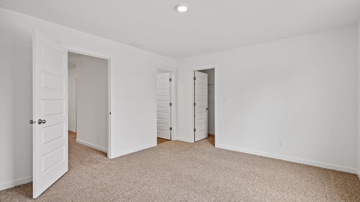 Primary bedroom with carpeted floors and a primary bathroom.