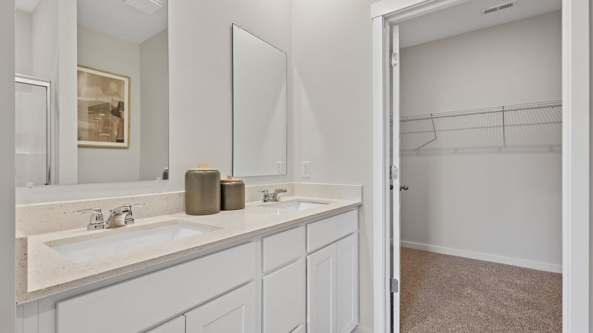 Dual vanity counters with mirrors and view of closet.