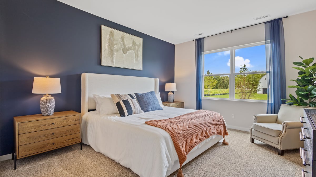 Primary bedroom with a big window and carpeted floors.