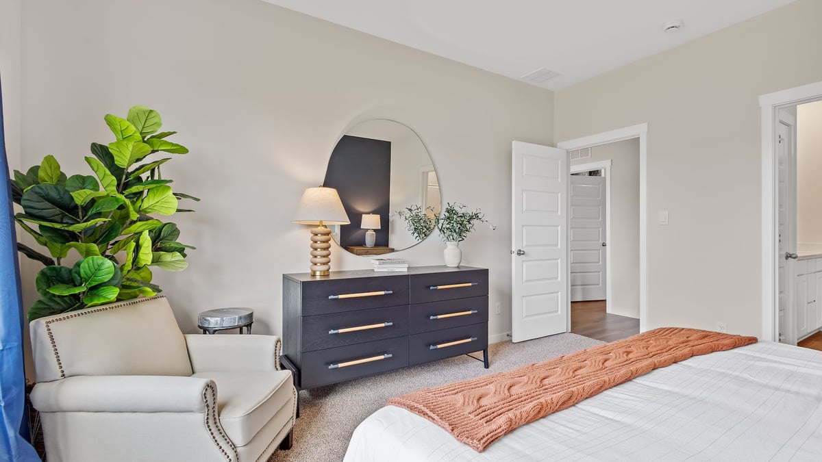 Primary bedroom with carpeted floors and view of dresser.