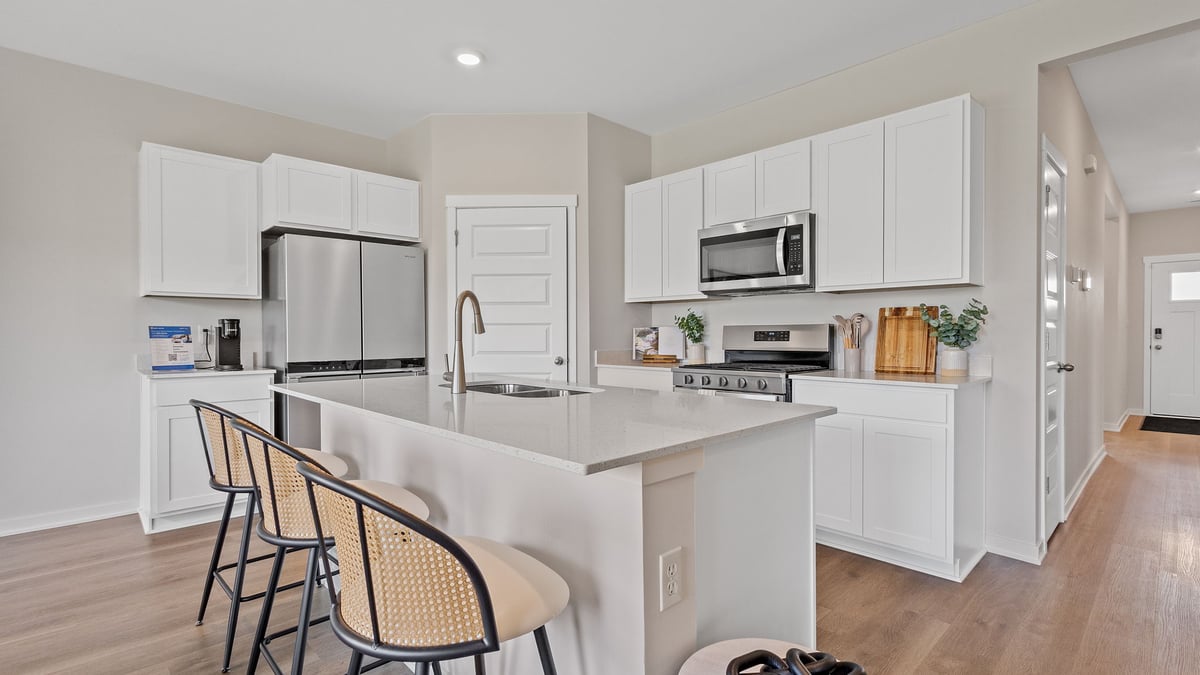 Kitchen area with white cabinets with hard wood flooring.