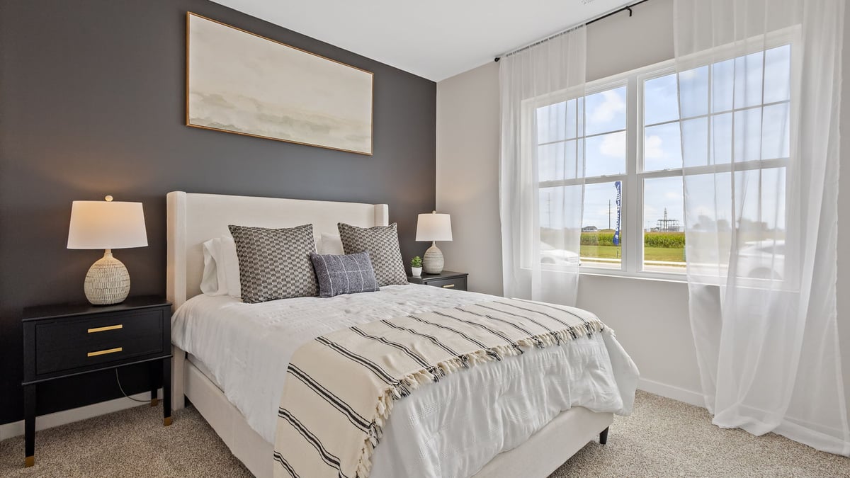 Bedroom with a big window and carpeted floors.