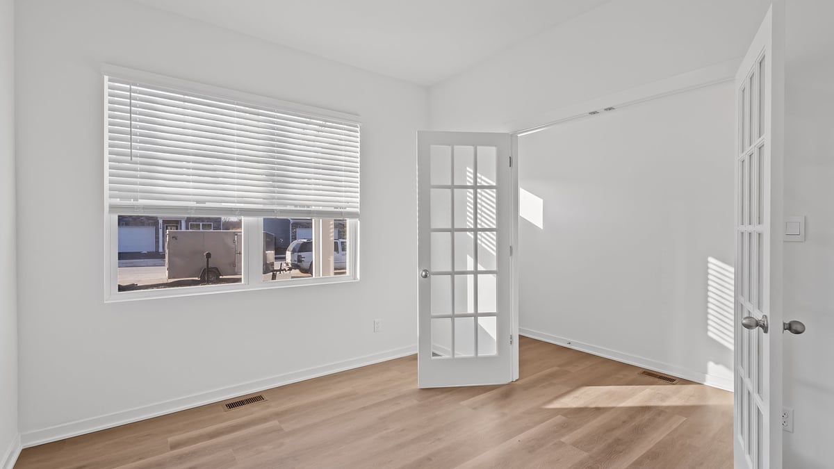 Front room area with hard wood flooring and a big window with french doors.