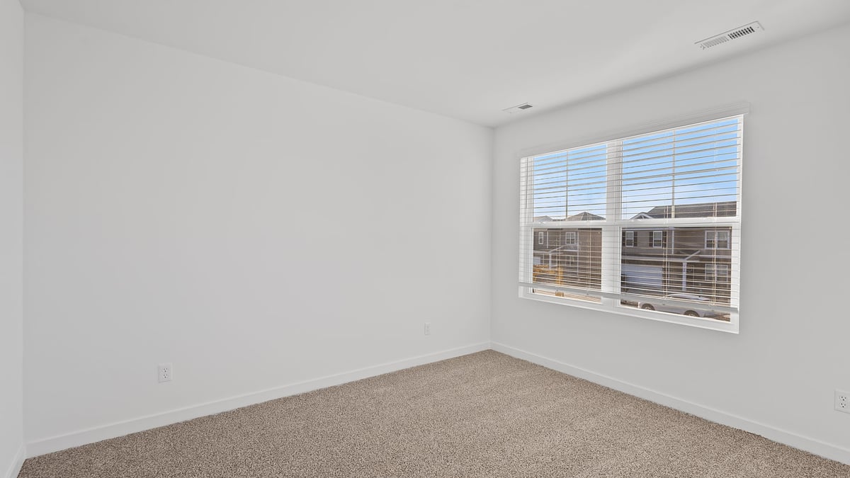 Bedroom with a big window and carpeted floors.