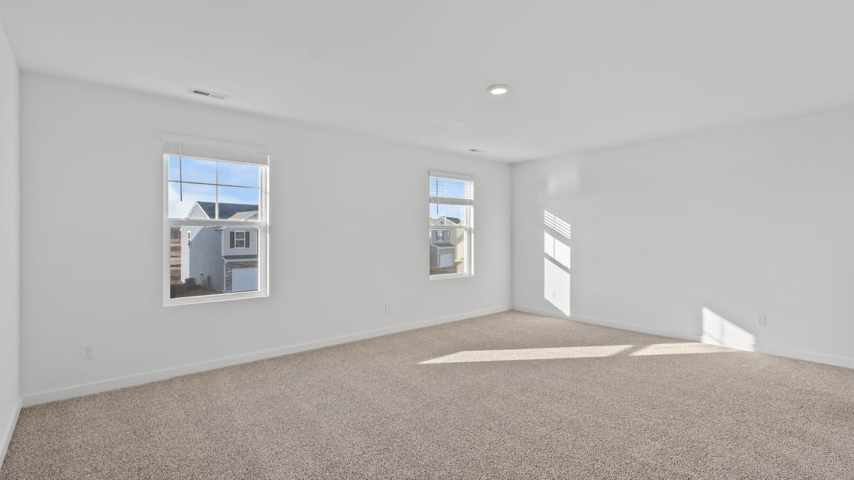 Primary bedroom with carpeted floors with windows and great amounts of space.