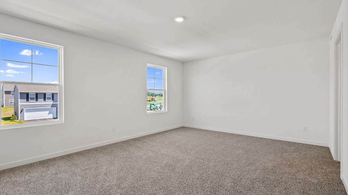 Primary bedroom with carpeted floors and two windows with great space.