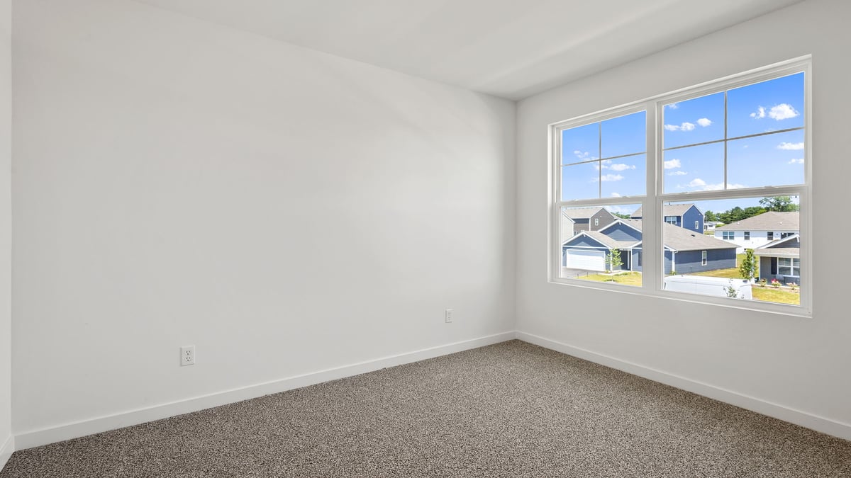 Bedroom with a big window and carpeted floors.