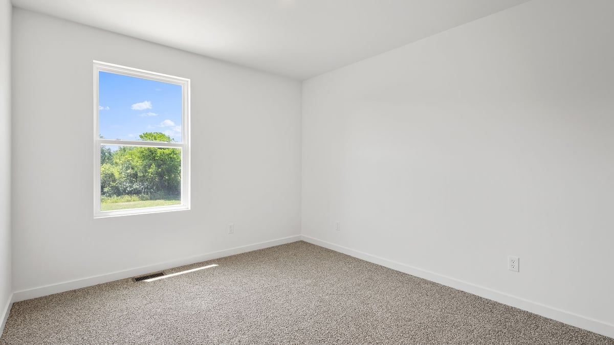 Bedroom with a side window with carpeted floors.