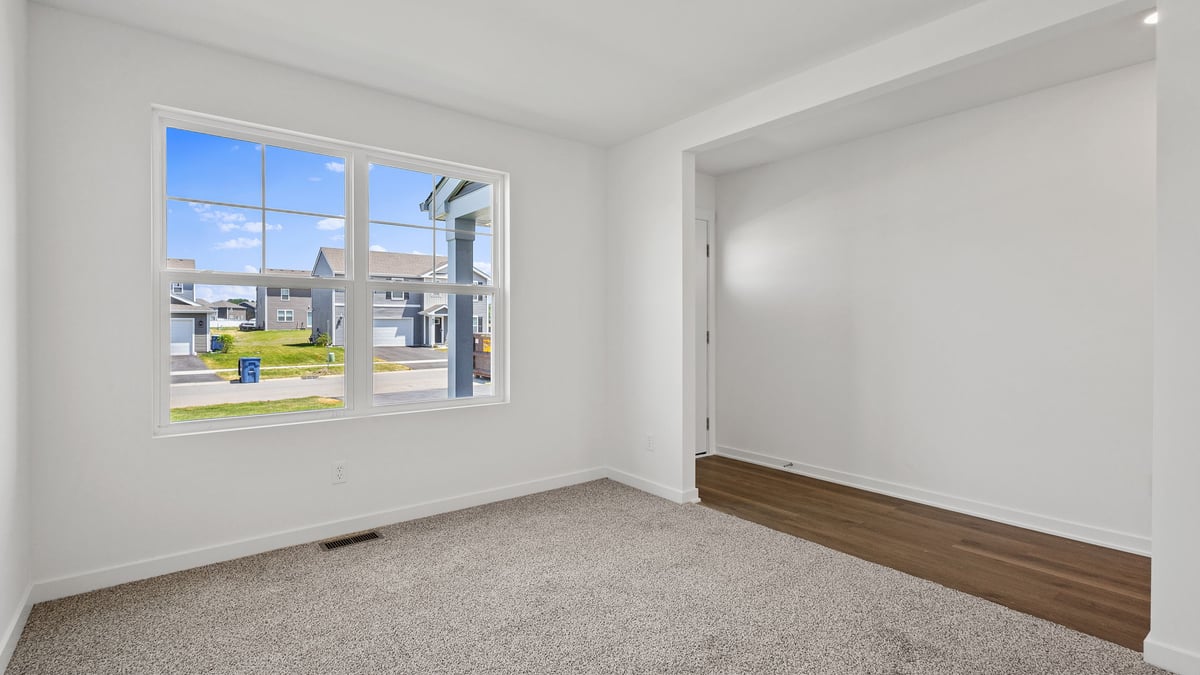 Front room with a big window and carpeted floors.
