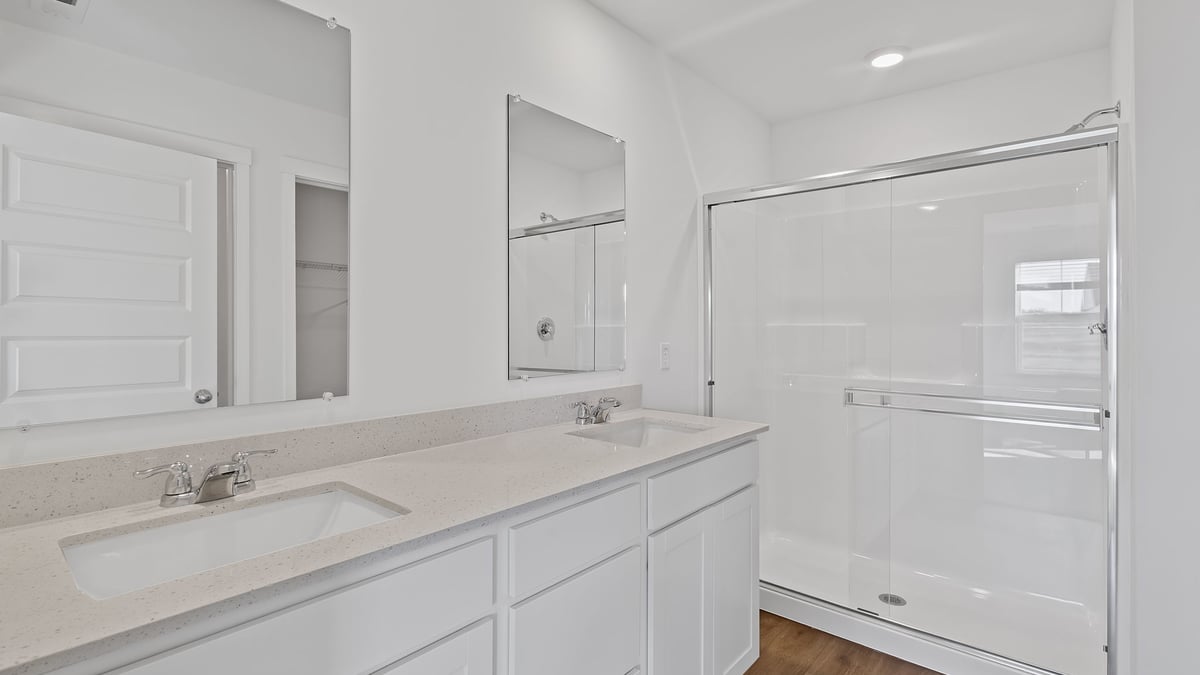 Primary bathroom with two vanity sinks and a walk-in shower.