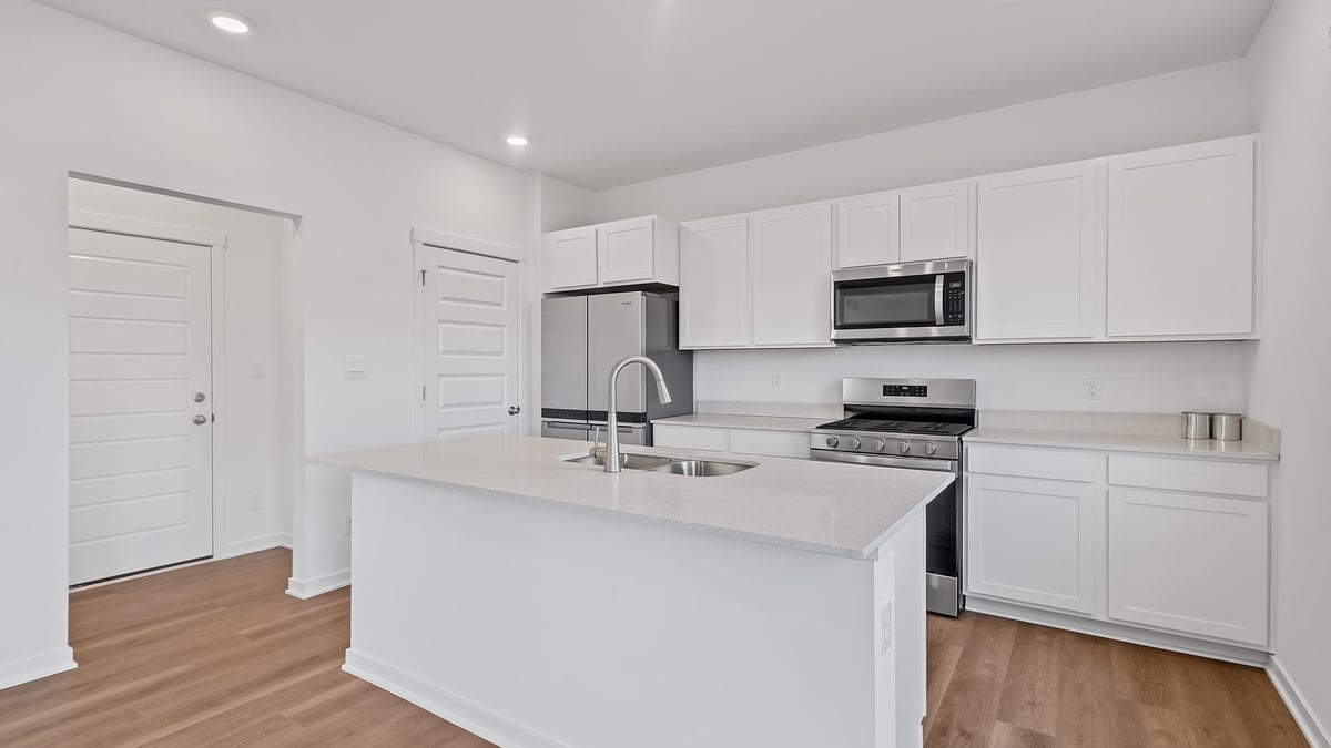 Kitchen area with white cabinets and hard wood flooring.