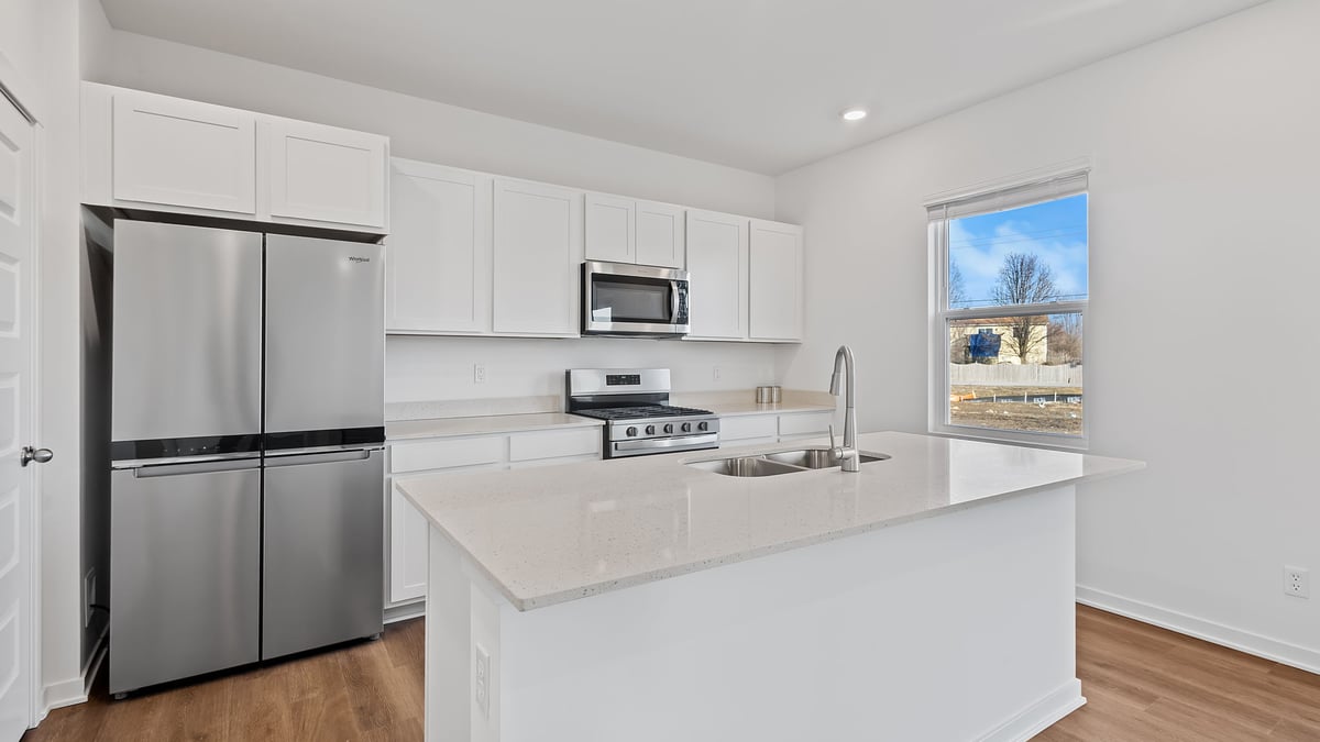 Kitchen with white cabinets and a side window and quartz countertops.