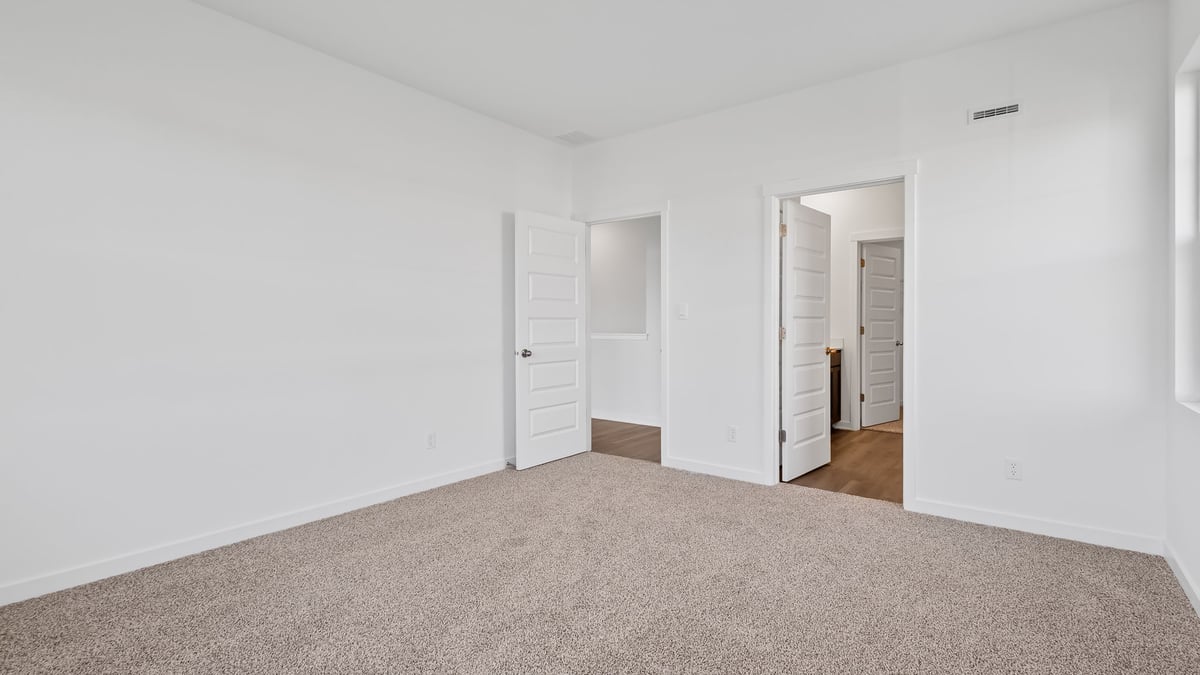 Primary bedroom with carpeted floors and own bathroom suite.