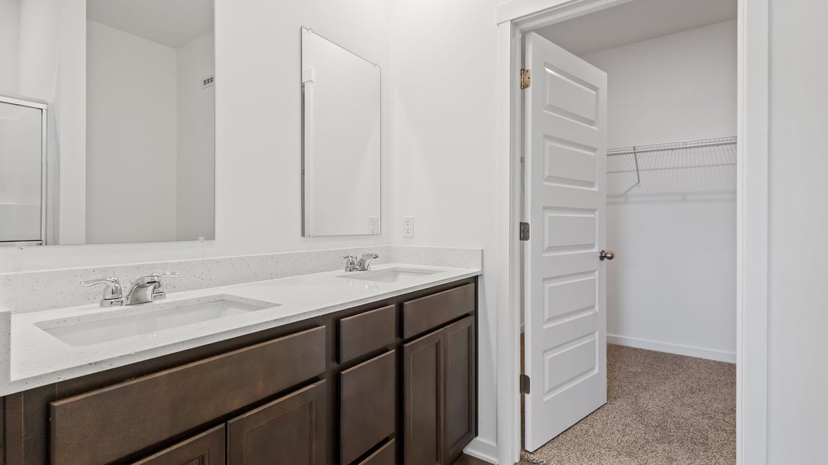 Primary bathroom with dual vanity sinks and a walk-in closet.