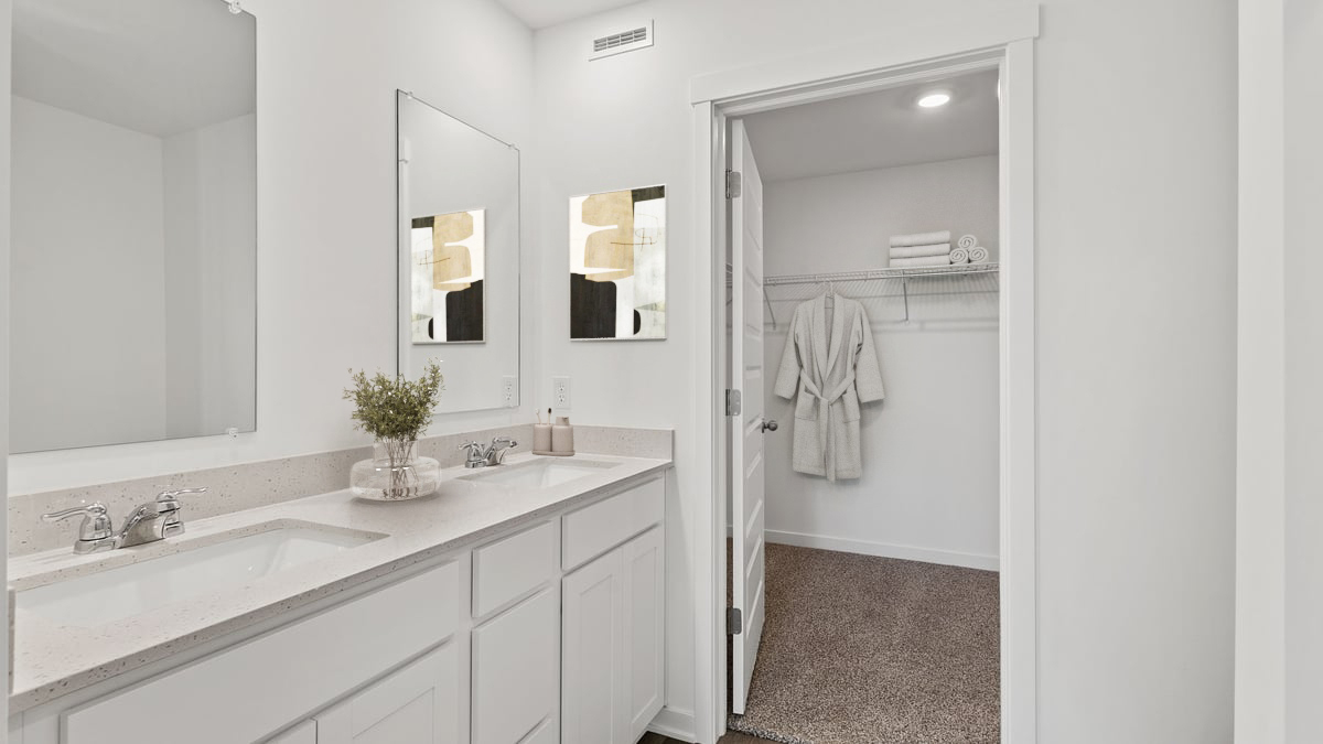 Primary bathroom with dual vanity sinks and walk-in closet.