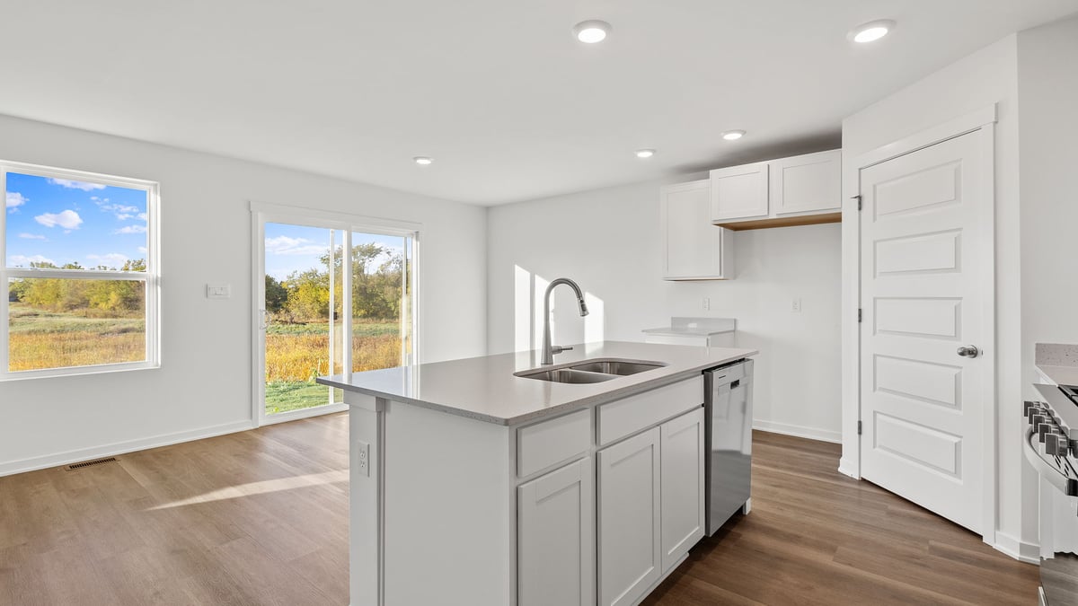 Kitchen island with a view of dining area with windows.