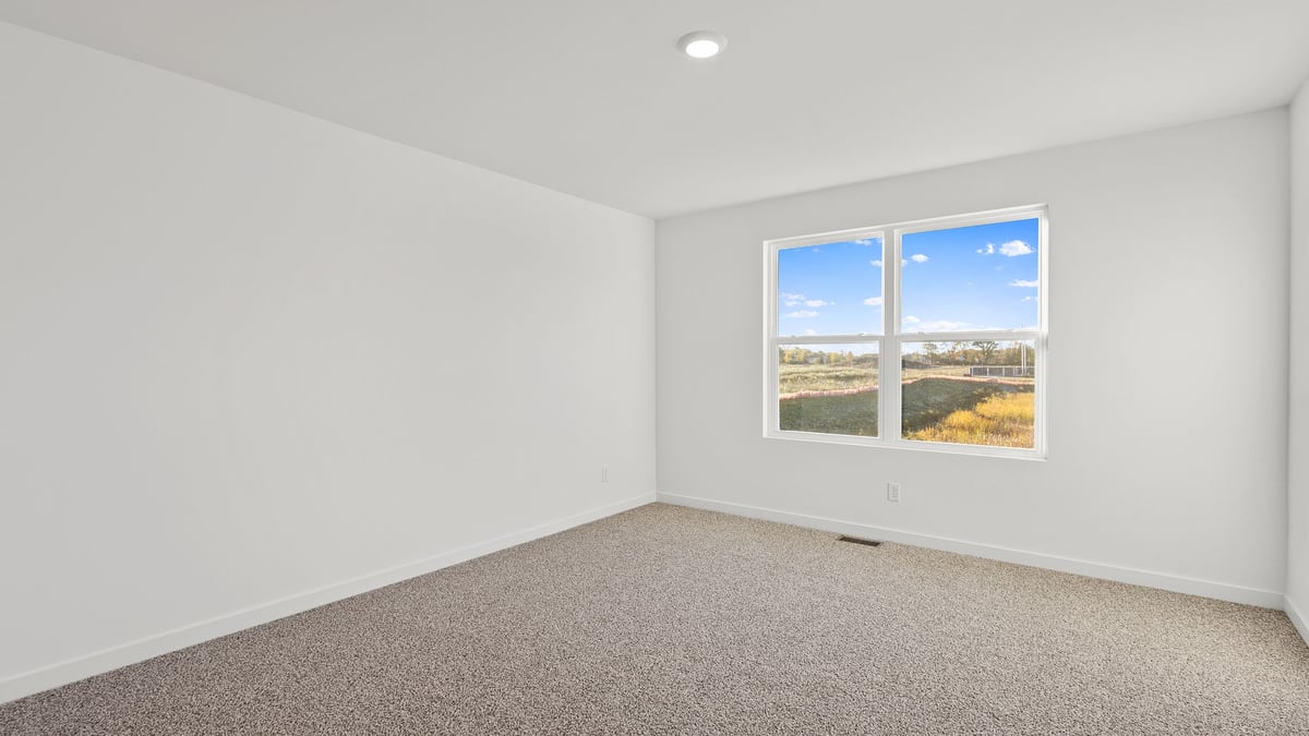 Primary bedroom with carpeted floors and a big window.