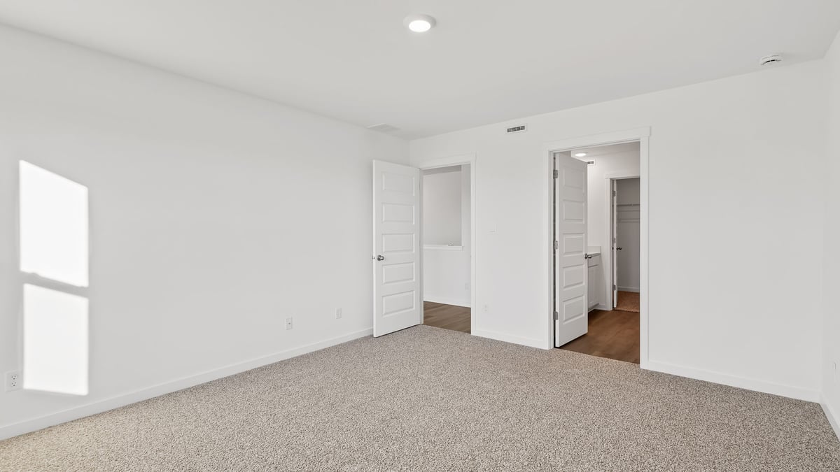 Primary bedroom with carpeted floors and a bathroom.