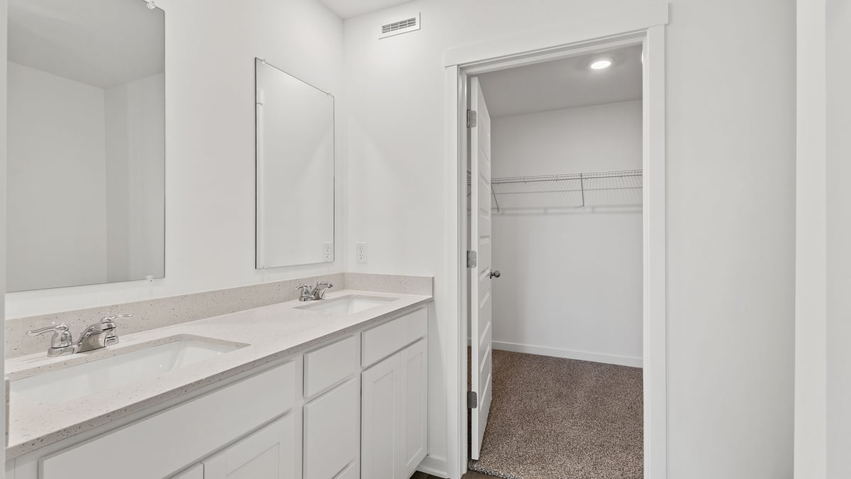 Bathroom with dual vanity sinks and a walk-in closet.