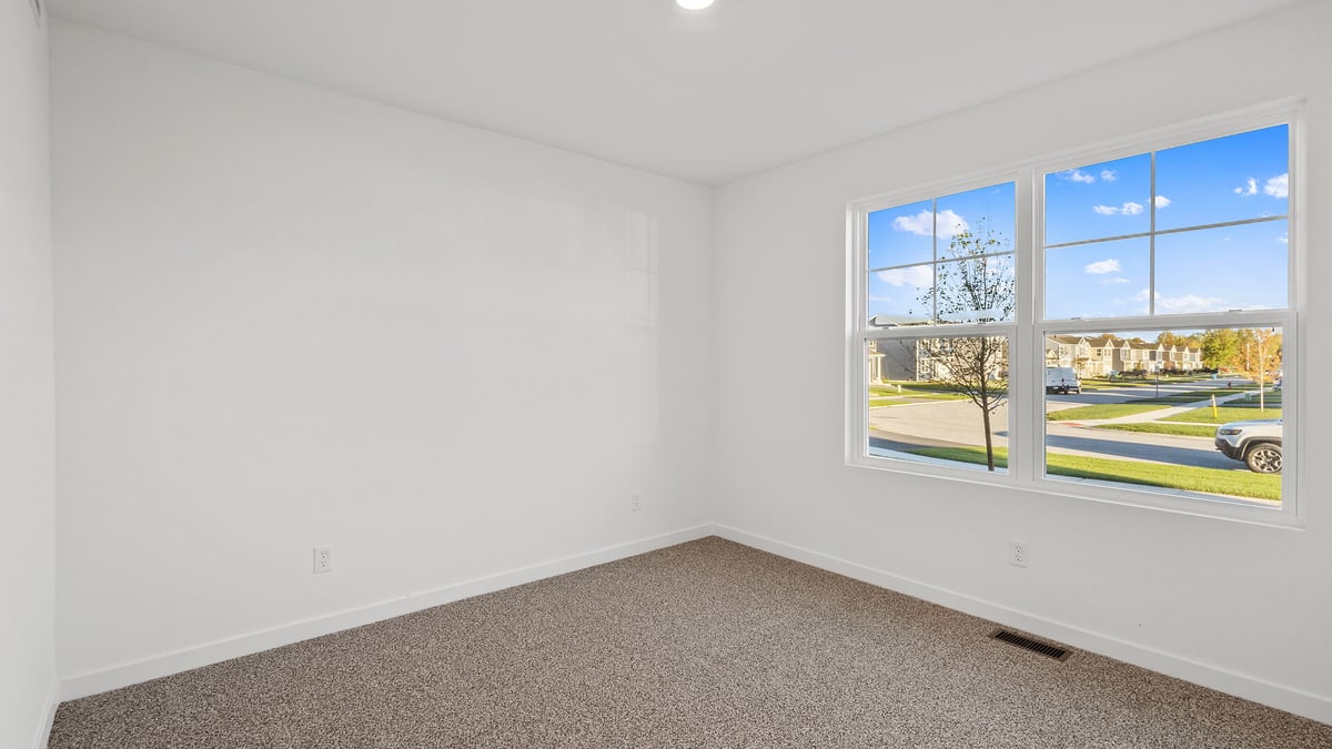 Bedroom with a big window and carpeted floors.