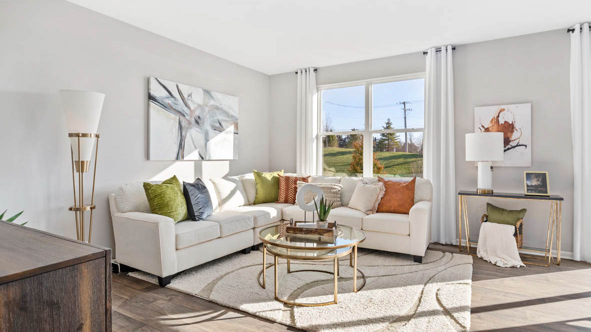 Living area with a large white sectional, an entertainment center, and large windows.
