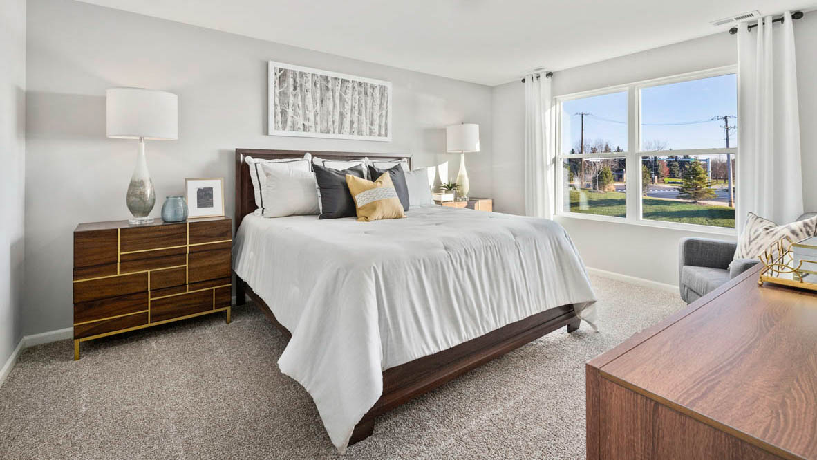 Bedroom featuring a large bed with grey bedding, two nightstands, and a large window.