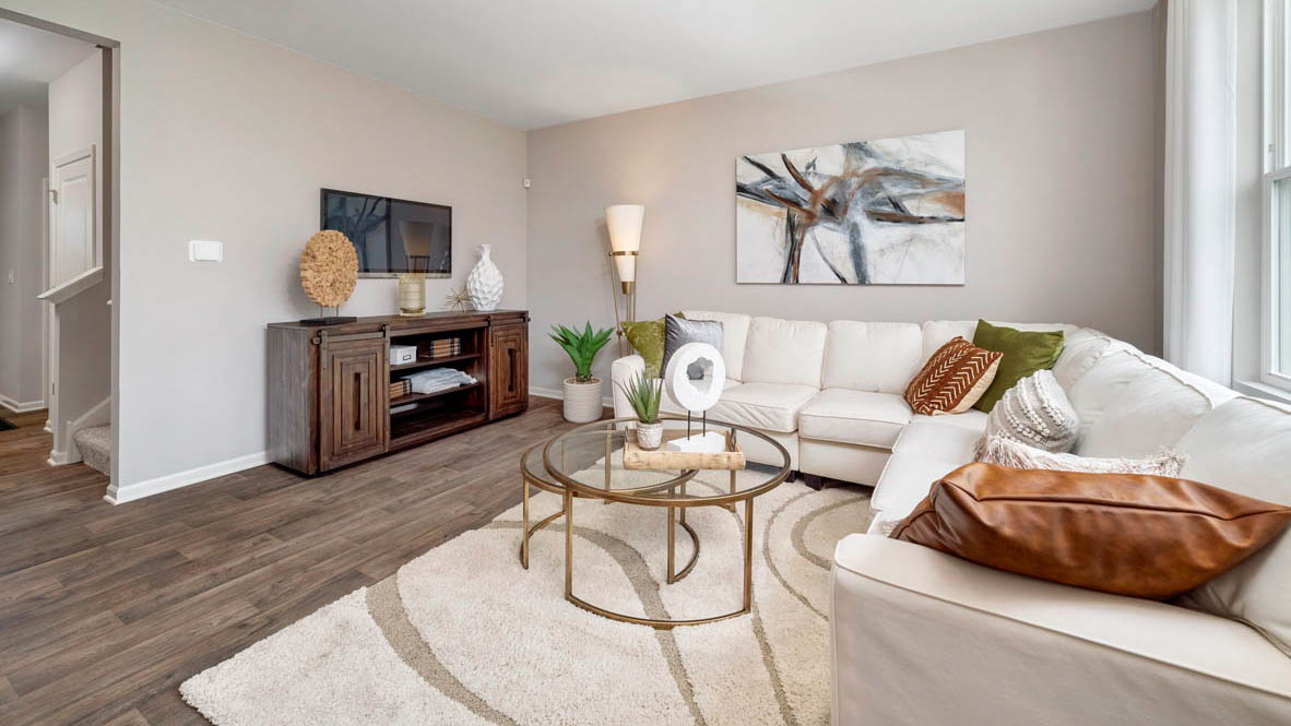 Living area with a large white sectional, an entertainment center, and natural lighting.