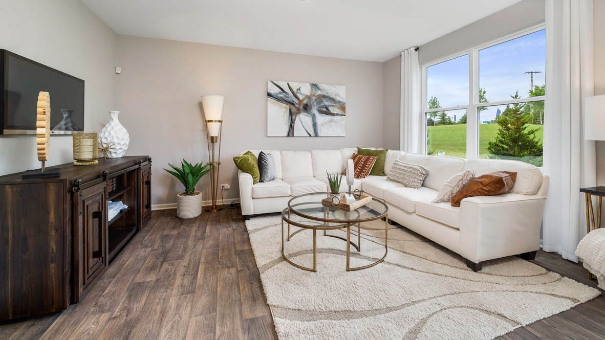 Living area with a large white sectional, an entertainment center, and large windows.
