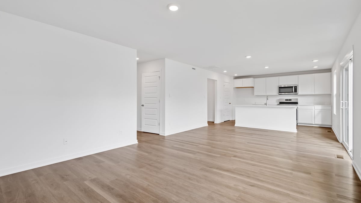 Living area viewing the kitchen with white cabinets.