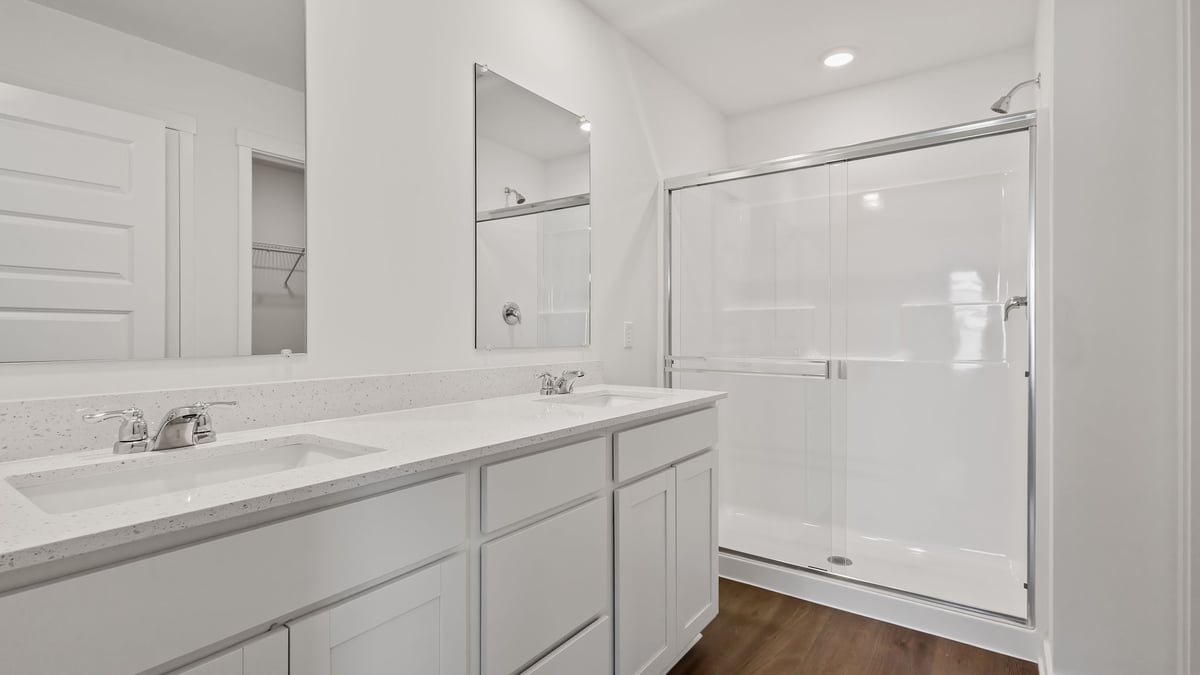 Primary bathroom with dual vanity sinks and a walk-in shower.