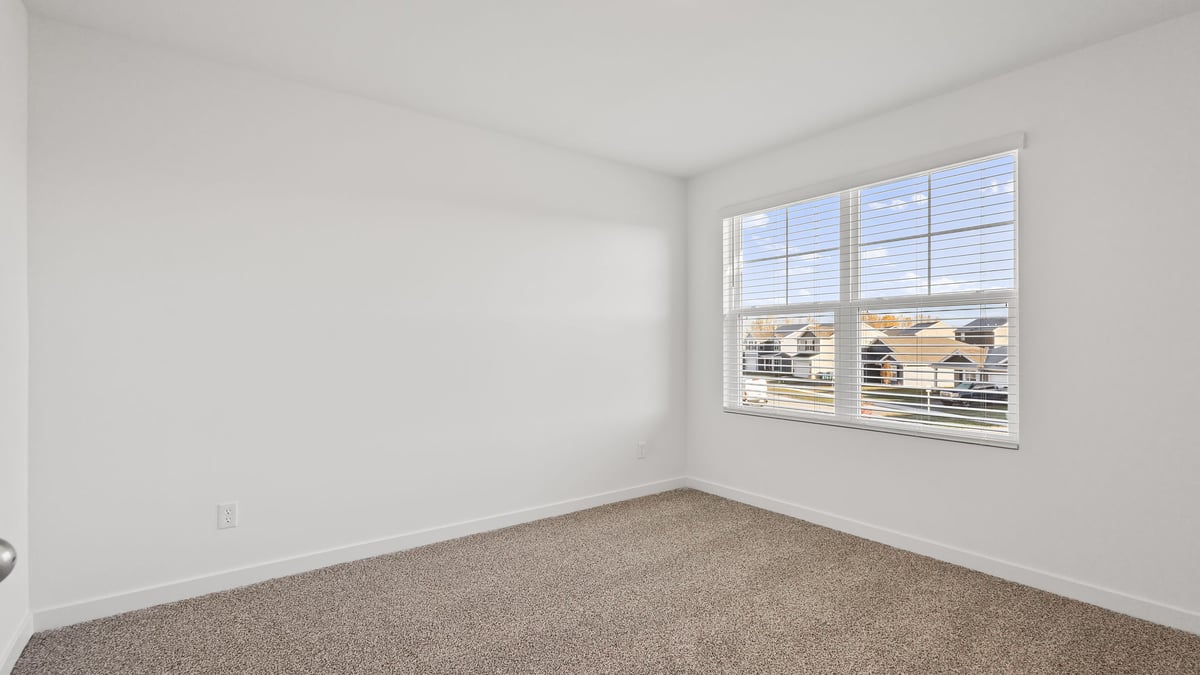 Bedroom with a big window and carpeted floors.