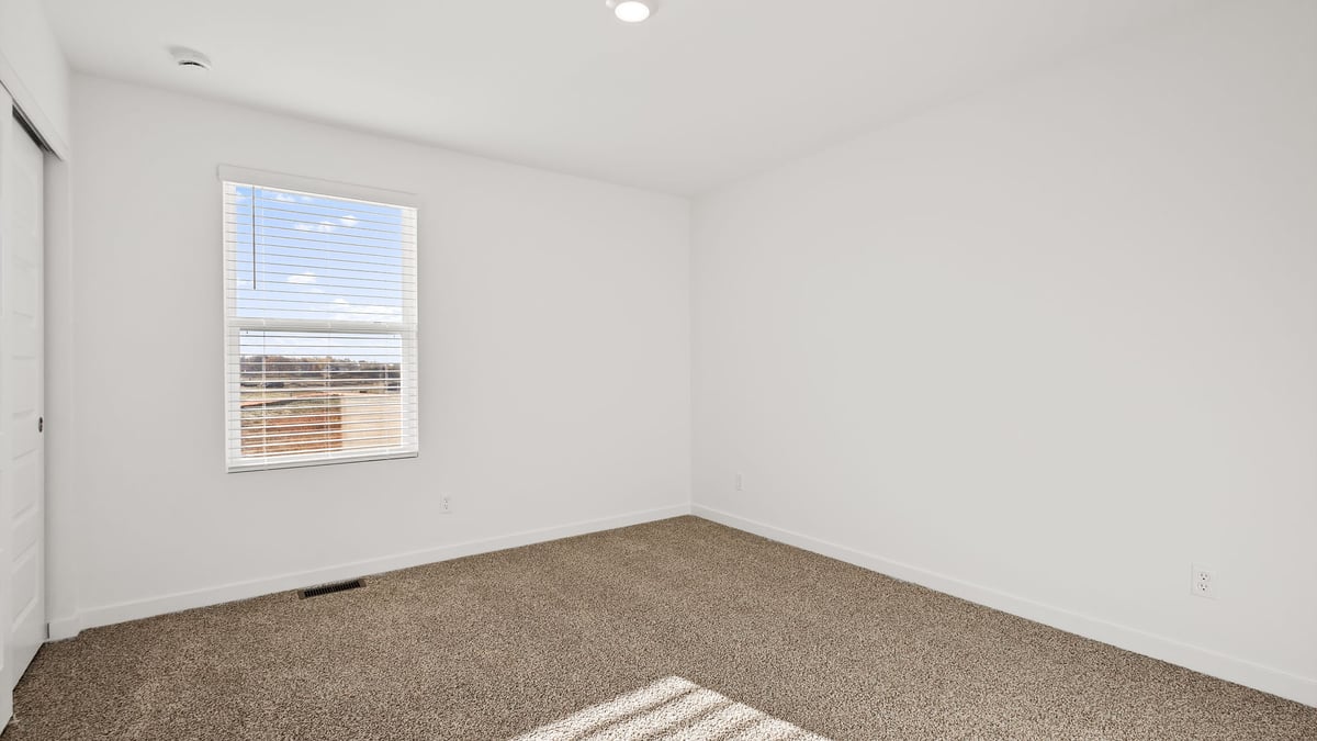 Bedroom with a side window and carpeted floors.