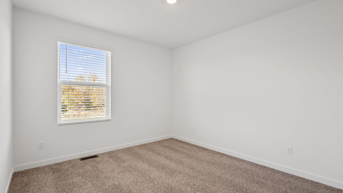 Bedroom with a side window and carpeted floors.