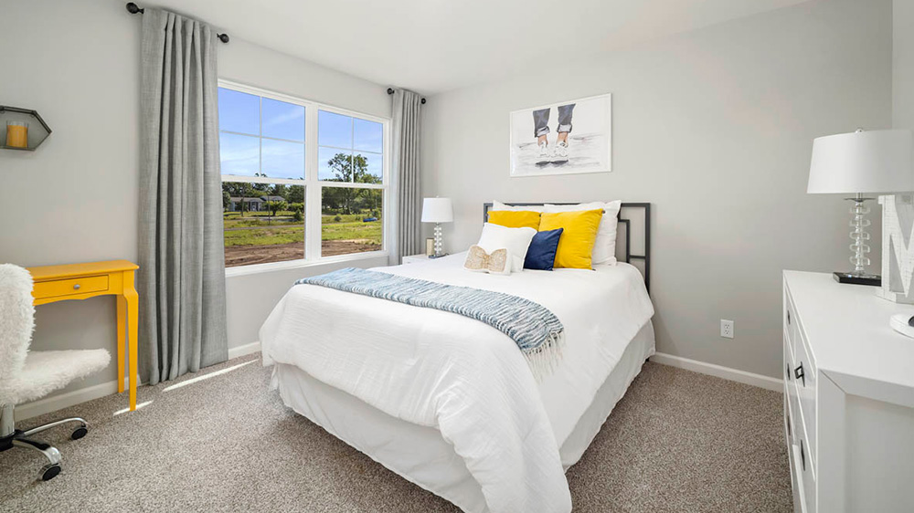 Bedroom with a big window and carpeted floors.