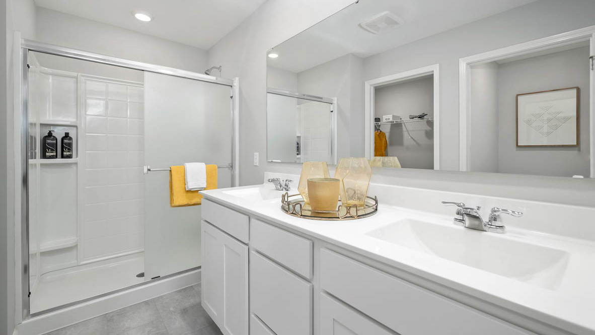 Primary bedroom with a walk-in shower and dual vanity sinks.
