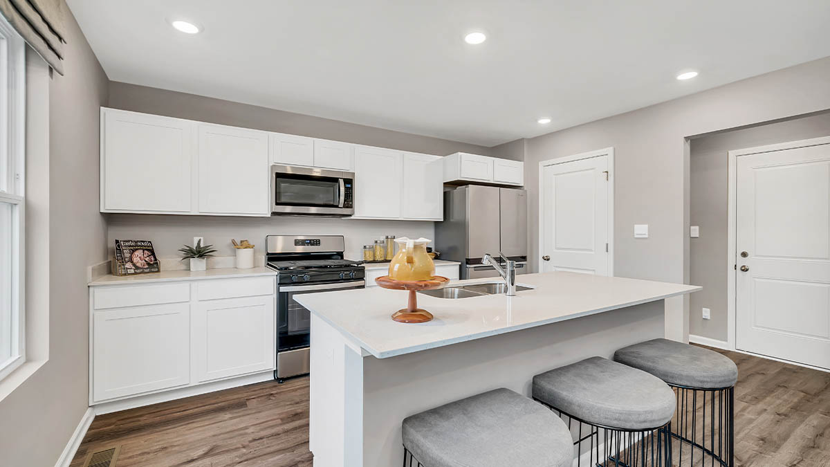 Kitchen area with white cabinetry and hard wood flooring.