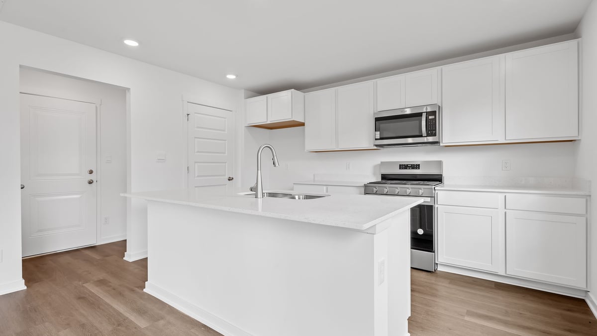 Kitchen with white cabinets and kitchen island with hard wood flooring.