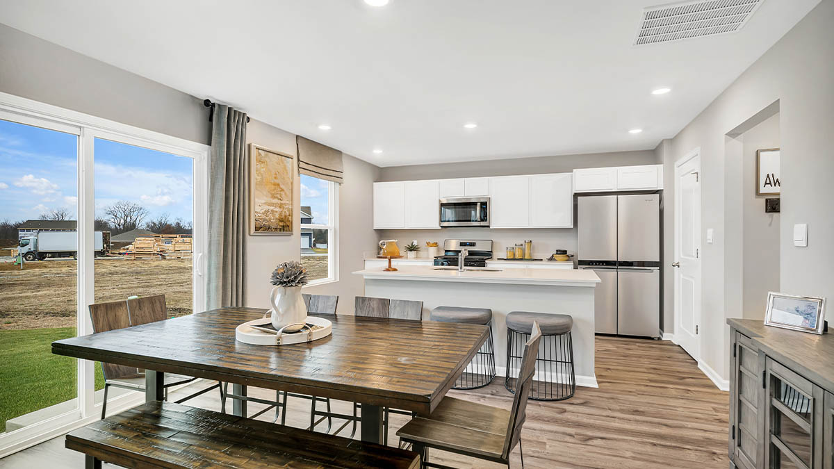 Dining area and kitchen area with a glass sliding door and hard wood floors.